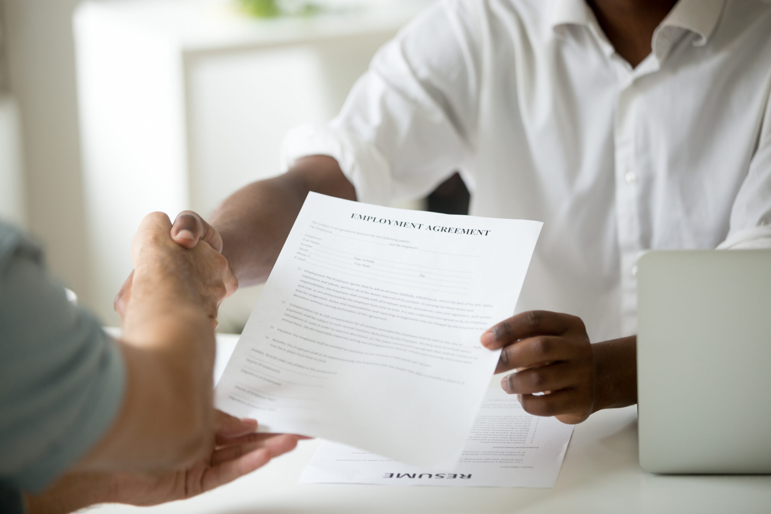 African-american employer holding employment agreement handshaki African-american employer holding employment agreement handshaki
